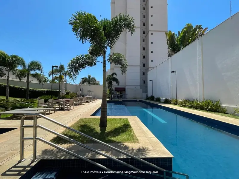 Piscina com palmeiras e deck no Living Welcome Taquaral